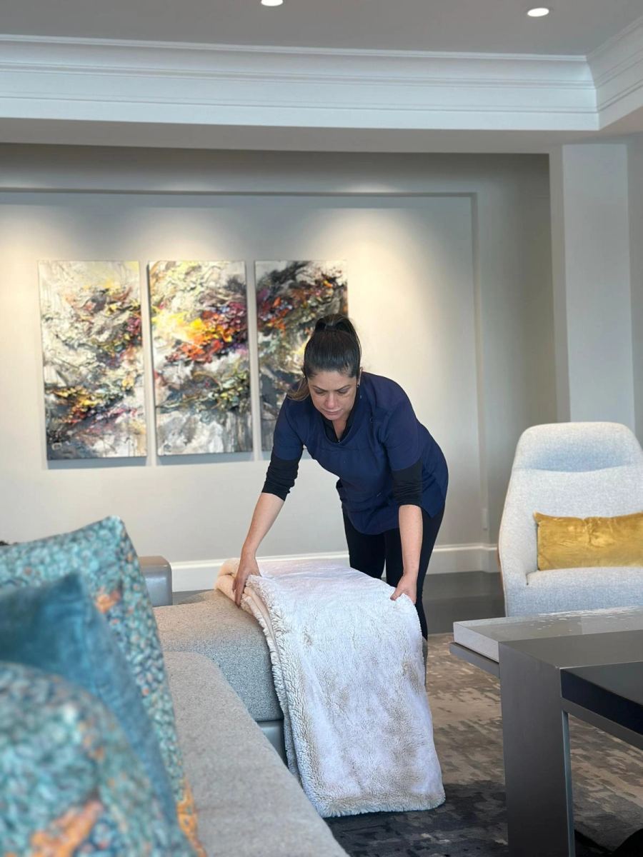 A Beeah's Cleaning team member fluffing pillows on a living room sofa